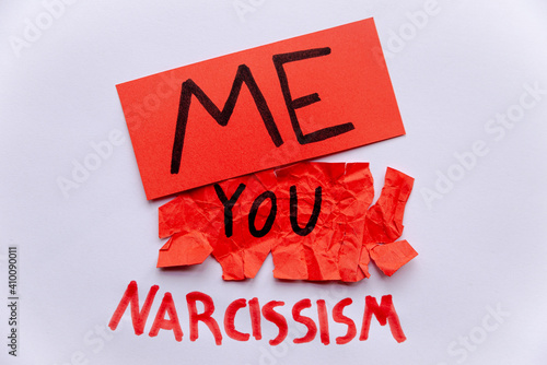 Pathological narcissism, narcissism and Gaslighting. Red paper with Me written on it, crumpled and torn red paper with You written on it, with Narcissism written next to it in red on a white paper.