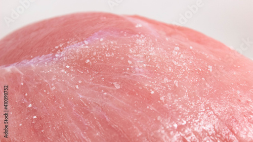 A piece of raw pork meat with salt on the surface.