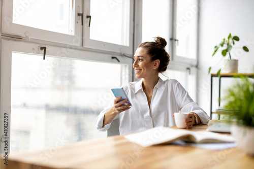 Creative business woman using smartphone in loft office 