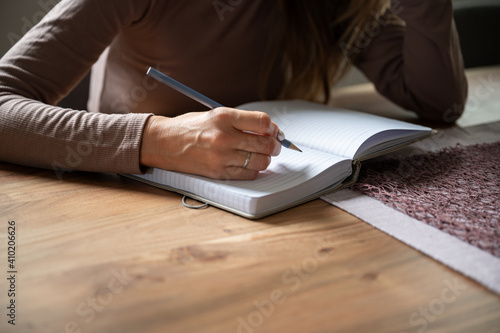 Closeup view of a woman writing in blank notebook