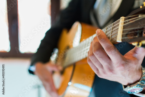 Foto de hombre sentado inclinado sostiene guitarra acústica instrumental tocando canción 
