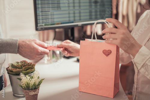 Man with credit card pays at the checkout buying gift in a female clothing store.