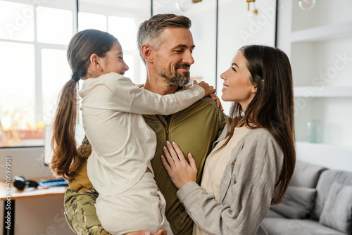 Happy masculine military man smiling and hugging his family indoors