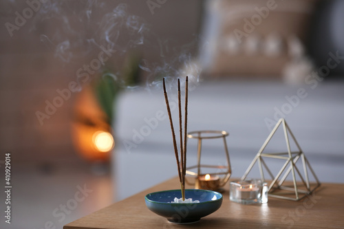 Incense sticks smoldering on table indoors, space for text