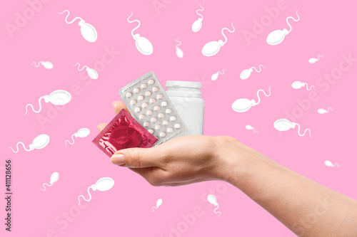 Hand with different contraceptive means on color background