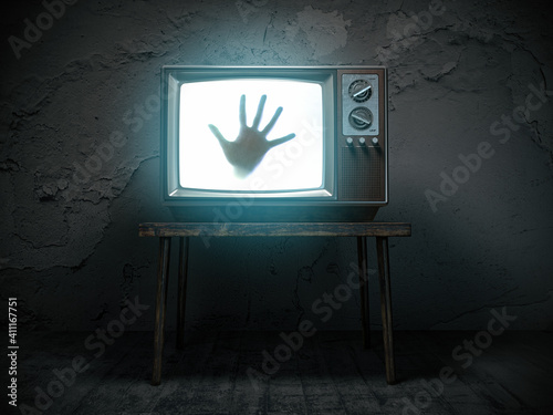 Horror scary movie concept. Hand of ghost on screen of vintage tv in haunted house.