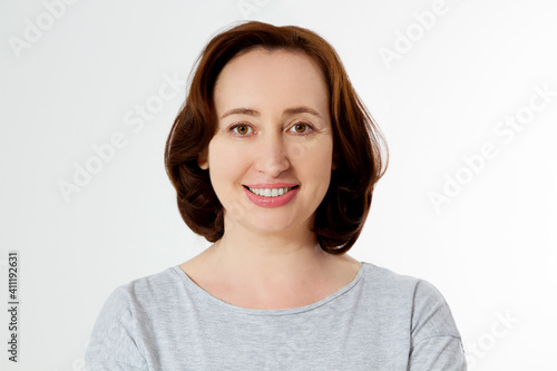 Closeup beautiful middle aged woman face isolated on white background with copy space. Anti aging lifting treatment and skincare routine. Menopausal female period and healthy anti-aging lifestyle