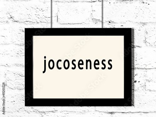 Black frame hanging on white brick wall with inscription jocoseness