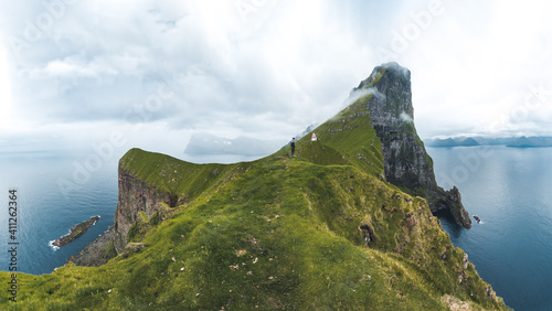 Kalsoy Island with Kallur lighthouse on on Faroe islands, Denmark, Europe. Clouds over high cliffs, turquoise Atlantic ocean and spectacular views.