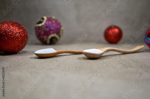 Two wooden spoons and christmas decorations in the background. 