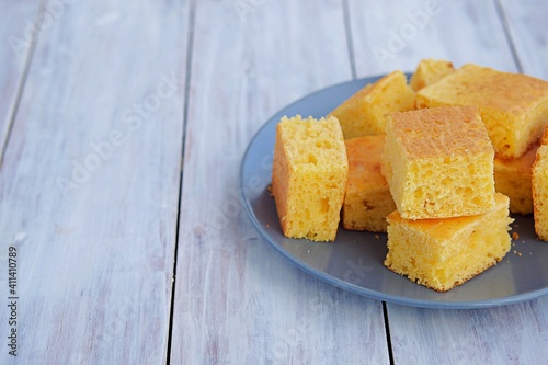 Sliced cornbread on a gray plate on a light wooden background. Corn flour recipes. C