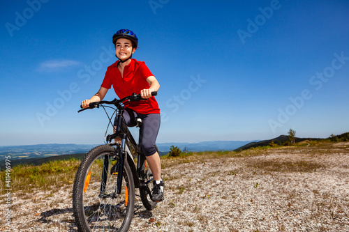 Young woman riding bicycle on country road 