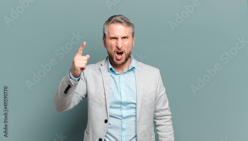 adult businessman pointing at camera with an angry aggressive expression looking like a furious, crazy boss