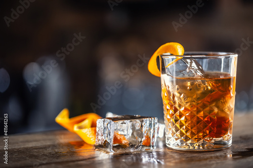 Old fashioned rum drink on ice with orange zest garnish