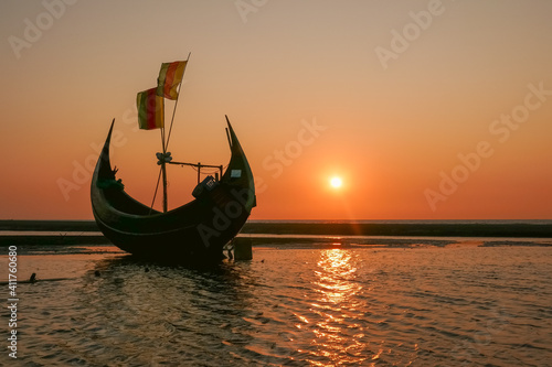 Sunset landscape view of traditional wooden fishing boat known as moon boat on beach near Cox's Bazar in southern Bangladesh