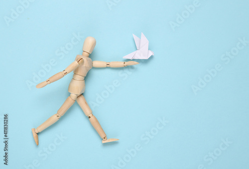 Wooden puppet with Origami dove on blue background