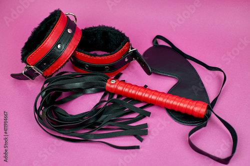 BDSM accessories on a purple background. A set of erotic toys, handcuffs, a whip and a mask. Diversity of sexual life