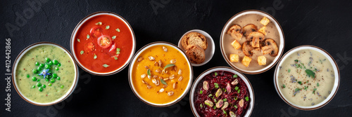 Vegan soup panoramic banner. Various vegetable soups, shot from above, a flat lay on a black background