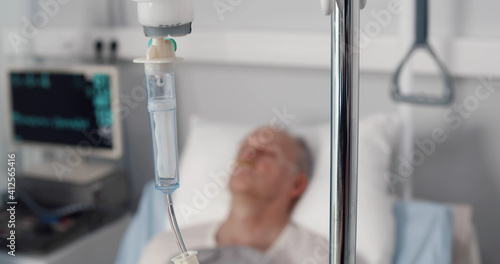 Senior man patient lying in hospital bed with dropper