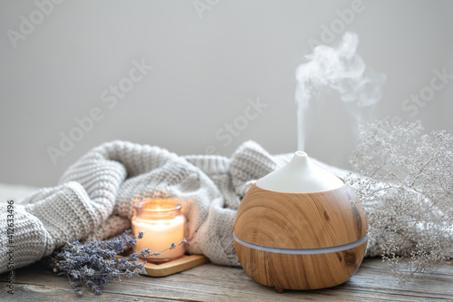 Cozy home composition with air humidifier, knitted element, lavender and candle copy space.