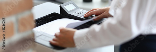 Woman in office prints documents on printer. Scanning documents at workplace concept