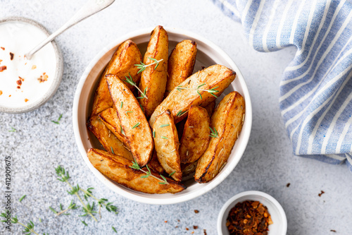 baked potato wedges with sauce on a light background, top view