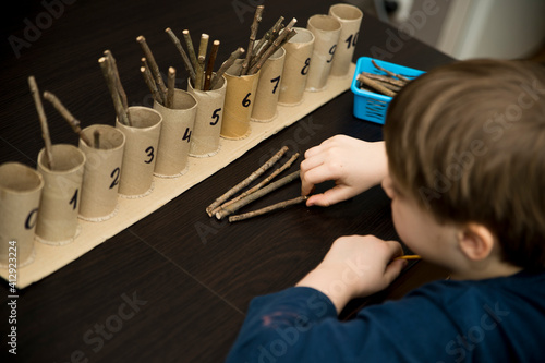 Little child doing simple math exercises. Early education, counting game. Preschool exercise for kids. Child learn to count to ten. Montessori math tool.