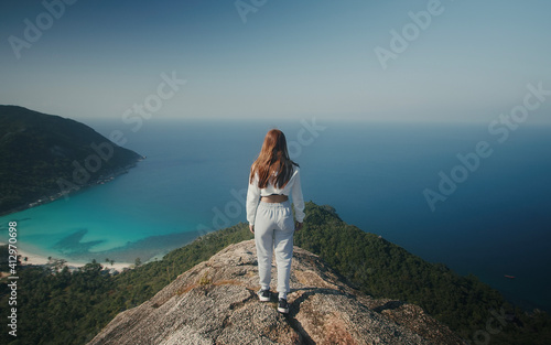 Traveler girl from behind on montain peak with sea view