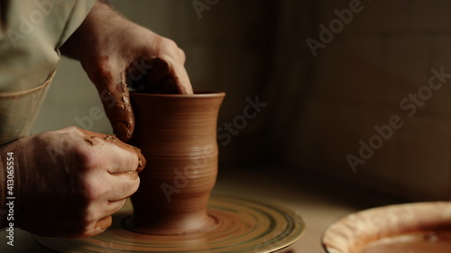 Unknown clay artist sculpting in studio. Man hands forming jar in pottery 