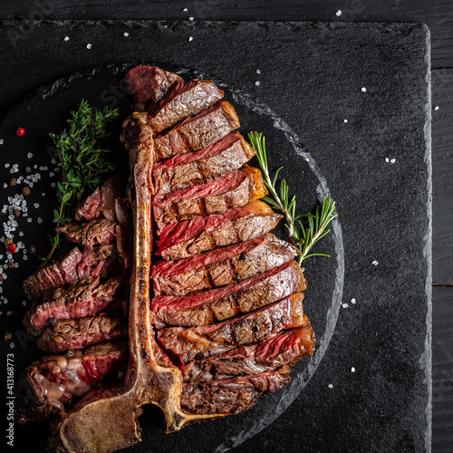 Dry Aged Barbecue Porterhouse Steak T-bone beef steak sliced with large fillet piece with herbs and salt. American meat restaurant. square image, top view