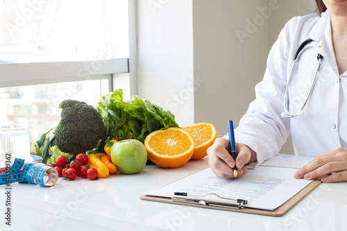 Female nutritionist doctor writing vegetable diet plan