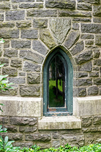 lancet style window with peeling paint on wood frame in a stone building with a keystone above the window