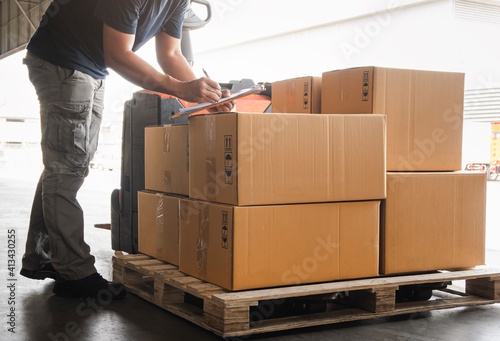 Warehouse worker holding clipboard his doing inventory management packaging boxes. Checking stock. Shipment boxes. Shipping warehouse logistics