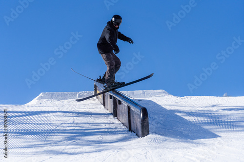 Skier sliding on a rail in a snowpark on a sunny day in Austria
