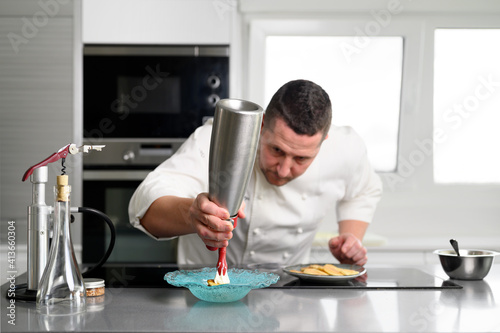 Professional chef holding a foam siphon in a restaurant kitchen. High quality photo