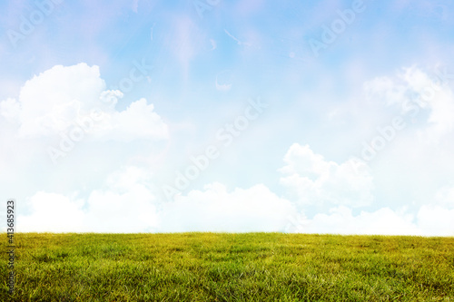 Abstract illustration of distressed overlay texture against green grass and clouds in blue sky in ba
