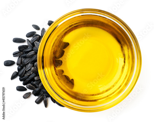 Sunflower oil in a plate and seeds on a white. Top view.