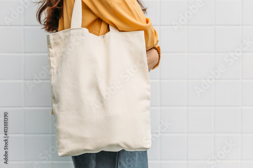 Woman is holding tote bag canvas fabric for mockup blank template.