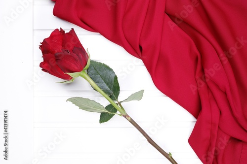 Czerwona róża i czerwona tkanina na białym blacie