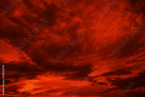 Abstract dark red background. Dramatic red sky. Red sunset with clouds. Fantastic sunset background with copy space for design. Halloween, armageddon, apocalypse, end of the world concept.