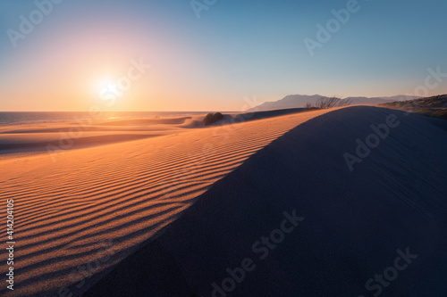 Atmospheric and mystical moody light of the sunset sunbeam illuminated the slope of a sand dune somewhere in the depths of the Sahara Desert