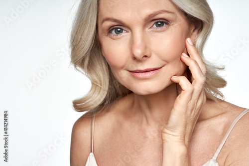 50s mid aged woman touching face skin looking at camera. Attractive mature old woman looking at camera isolated on white background advertising dry skin care treatment anti age skincare. Close up view