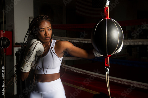 Young black woman training boxing in gym with the ring boxing background. Determination, training, perseverance.