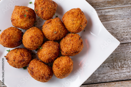 A top down view of a plate of deep fried hush puppies.