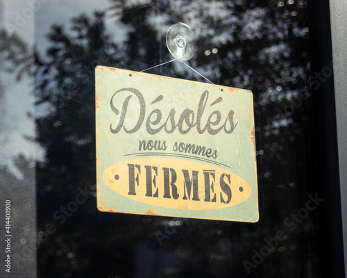 Sign written in French on shop window reads 'sorry, we are closed', in France