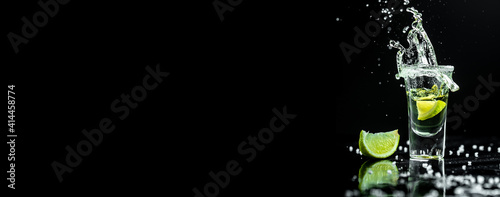 Mexican tequila with lime and salt on rustic black background. space for text. concept luxury drink. Alcoholic drink concept. Freeze motion, drops in liquid splash. Long banner format