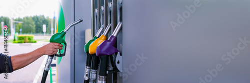 Man holds a refueling gun in his hand for refueling cars. Gas station with diesel and gasoline fuel close-up.