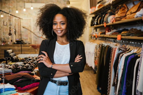 Portrait with folded arms a young beautiful owner of clothes shop at entrance of commercial activity - Millennial starts a new start-up activities in her city - Sales assistant waits for customers