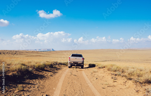 Car driving on sandy off road with dry grass