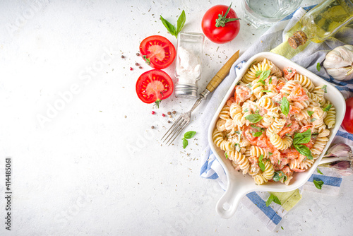 Spring diet healthy vegan pasta. Italian fusilli pasta with tomatoes, green vegetables, fresh herbs, cream cheese or feta, on dark table background copy space